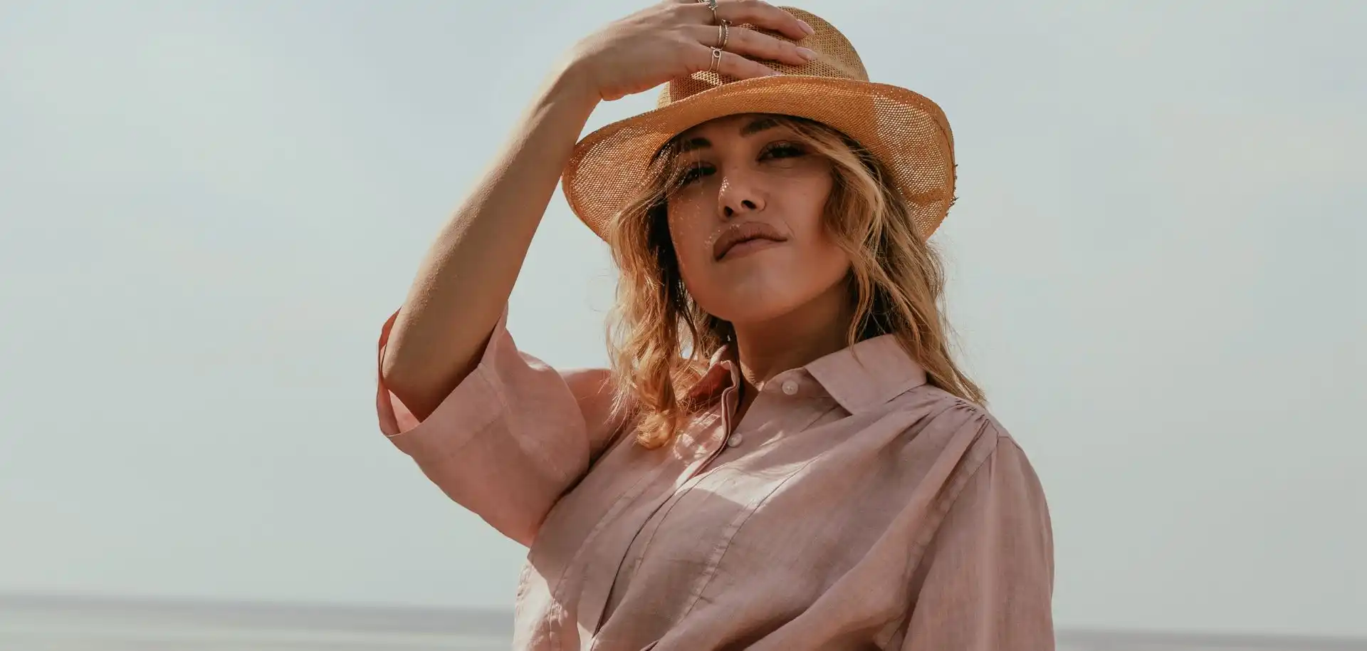 Ritratto donna in abbigliamento estivo con cappello di paglia e camicia in lino rosa